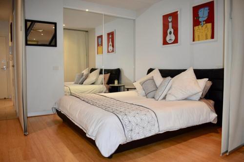a bedroom with a large bed and a mirror at Spacious 1 Bedroom Apartment in the Heart of Melbourne's CBD in Melbourne