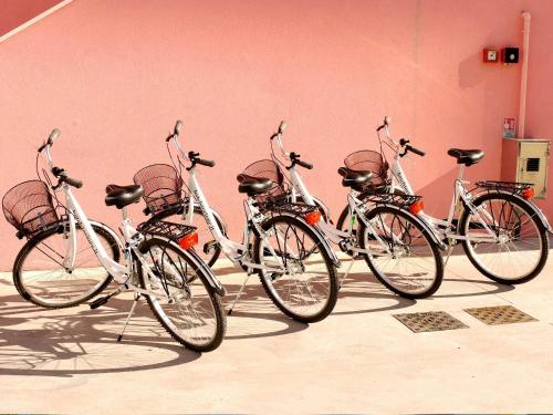 four bikes lined up against a pink wall at Hotel Storione in Lido di Jesolo