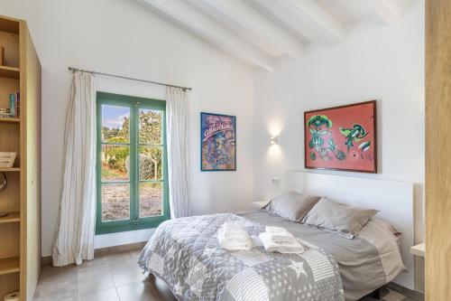 een witte slaapkamer met een bed en een raam bij Sa Verdal in Selva