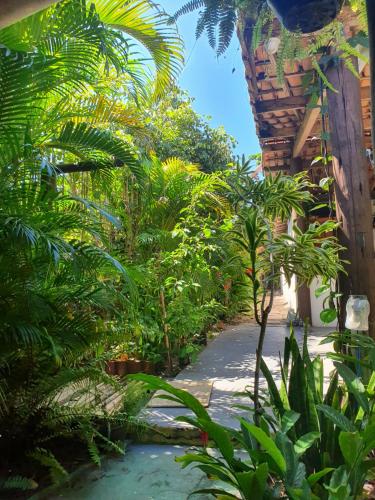 a garden with palm trees and plants on a sidewalk at Pousada Corais Do Sul in Caraíva