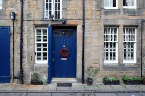 a blue door on a stone building with a wreath at Quiet Ground Floor Mews Flat and parking in Edinburgh