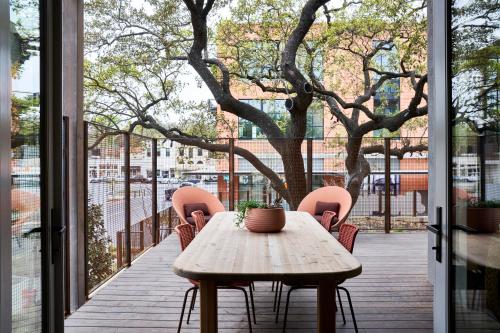a wooden table and chairs on a balcony with a tree at Hotel Magdalena in Austin