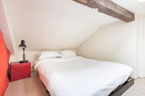 - une chambre avec un lit blanc et une table de nuit rouge dans l'établissement Modern Apartment in the Heart of the Marais, à Paris