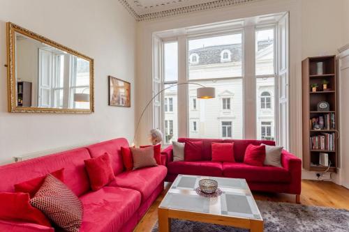 a red couch in a living room with a mirror at Cozy 2 Bedroom Apartment at Heart of the Edinburgh in Edinburgh