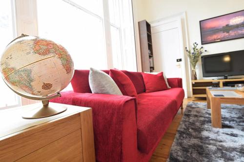 a living room with a red couch and a globe on a table at Cozy 2 Bedroom Apartment at Heart of the Edinburgh in Edinburgh