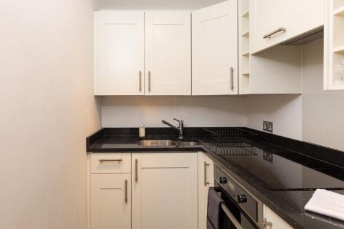 una cocina con armarios blancos y fregadero en Professionally Cleaned 1 Bed flat in South Kensington, en Londres