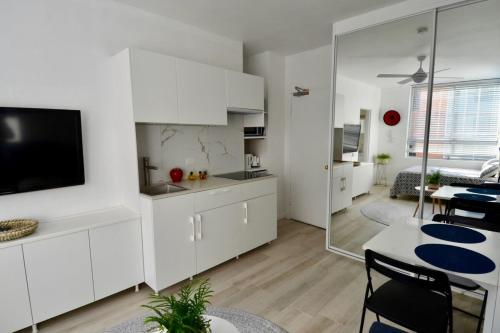 une cuisine avec des placards blancs et un salon dans l'établissement Cute Studio Apartment in Maroubra, à Sydney
