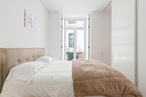 a bedroom with a bed with white sheets and a window at Spacious 1 Bedroom Apartment near Baixa in Lisbon
