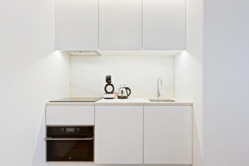 a white kitchen with a sink and a microwave at Spacious 1 Bedroom Apartment near Baixa in Lisbon