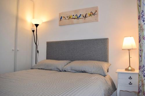 een slaapkamer met een bed met een grijs hoofdeinde en 2 lampen bij 2 Bedroom Apartment near historical Christchurch in Dublin