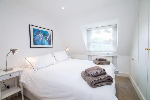 een slaapkamer met een wit bed en handdoeken bij Contemporary 1 Bed Flat in Fulham Near The Thames in Londen
