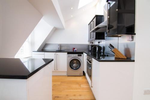 een keuken met een wasmachine en droger. bij Contemporary 1 Bed Flat in Fulham Near The Thames in Londen