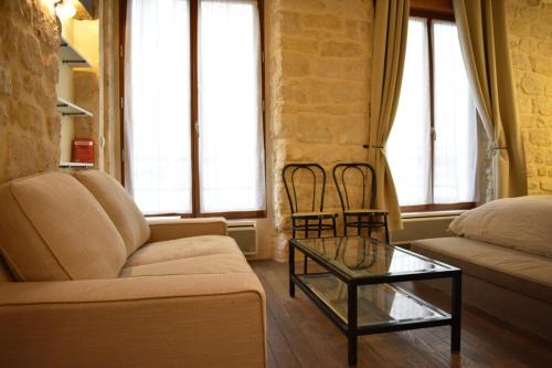 un salon avec un canapé et une table en verre dans l'établissement Charming studio near République and Le Marais, à Paris