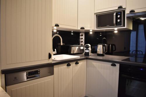 une cuisine avec des armoires blanches et un micro-ondes dans l'établissement Charming studio near République and Le Marais, à Paris