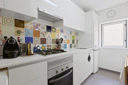 a white kitchen with a stove and a window at Stunning 1 Bedroom Apartment near Alfama in Lisbon