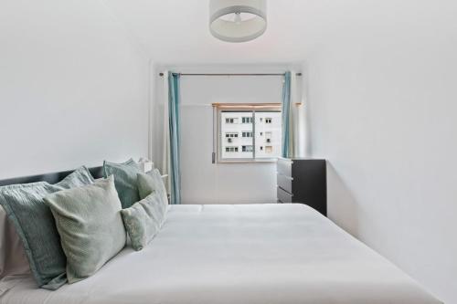 ein Schlafzimmer mit einem weißen Bett mit Kissen und einem Fenster in der Unterkunft Spacious 3 Bedroom Apartment in Lisbon in Lissabon
