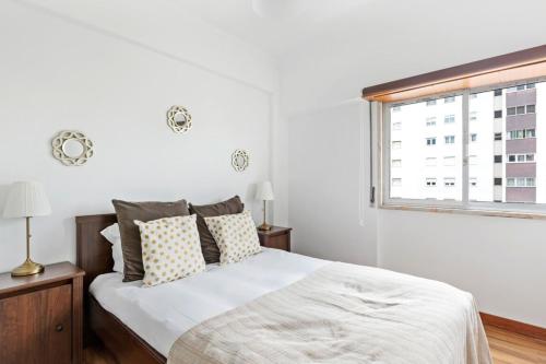 ein weißes Schlafzimmer mit einem Bett und einem Fenster in der Unterkunft Spacious 3 Bedroom Apartment in Lisbon in Lissabon