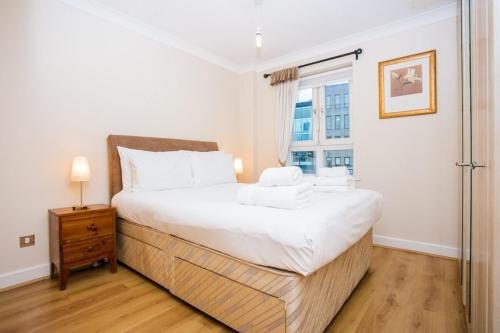 una camera da letto con un grande letto bianco e una finestra di 1 Bedroom Apartment on The Riverbank Near St Paul's a Londra