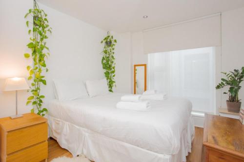 a white bedroom with a white bed with plants on it at Trendy East London Apartment near Shoreditch in London