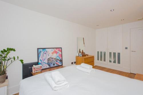 a bedroom with a white bed with two towels on it at Trendy East London Apartment near Shoreditch in London