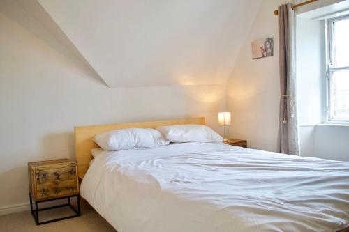 a bedroom with a large white bed with a window at Modern and Charming 2 Bedroom Old Town Apartment in Edinburgh