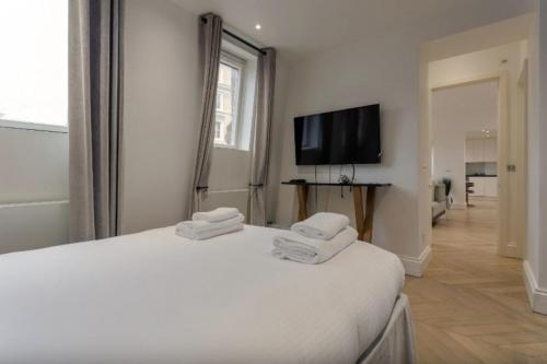 a white bedroom with two beds and a flat screen tv at Elegant 1 Bedroom Apartment in South Kensington in London
