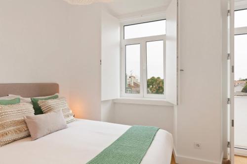 a white bedroom with a bed and two windows at Modern Portuguese 1 Bedroom Apartment in Belém in Lisbon