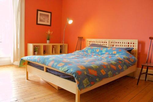 a bedroom with a bed with an orange wall at Classic Edinburgh Flat in the heart of Morningside in Edinburgh