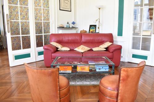 un salon avec un canapé rouge et deux chaises dans l'établissement Charming 2 Bedroom Apartment with view of Paris Gare de Lyon, à Paris