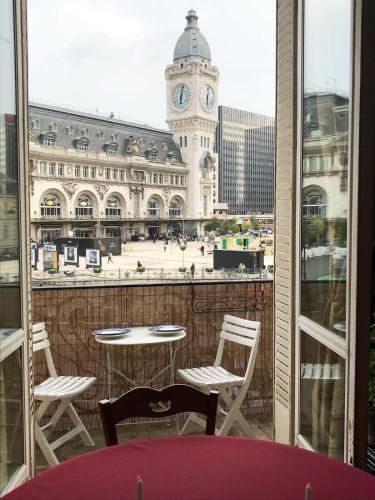d'un balcon avec une table, des chaises et une tour d'horloge. dans l'établissement Charming 2 Bedroom Apartment with view of Paris Gare de Lyon, à Paris