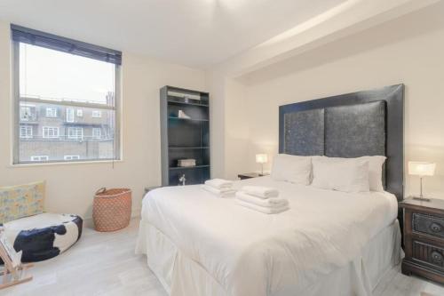 - une chambre avec un grand lit blanc et une fenêtre dans l'établissement Stunning Modern Apartment in South Kensington, à Londres