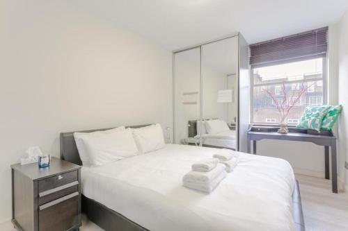 ロンドンにあるStunning Modern Apartment in South Kensingtonのベッドルーム1室(白いベッド1台、タオル付)