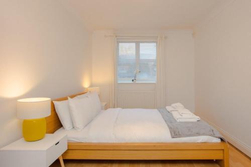 a white bedroom with a bed and a window at Contemporary 1Bedroom Flat in Camberwell Oval in London