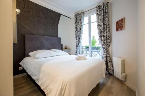 une chambre avec un grand lit blanc avec une fenêtre dans l'établissement Modern arty flat close to Saint-Germain des Près, à Paris