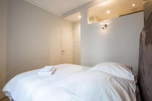 1 dormitorio con 1 cama blanca y 2 toallas en Modern arty flat close to Saint-Germain des Près, en París
