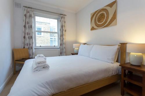 a bedroom with a large bed and a window at Bright and Spacious 1 Bedroom Apartment in the Heart of Kensington in London
