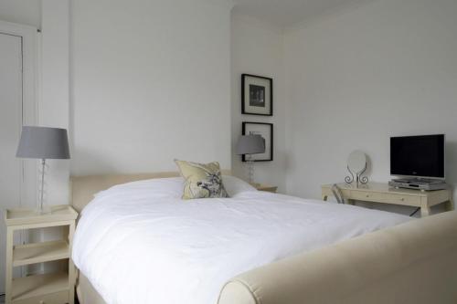 a white bedroom with a bed and a television at Stylish 2 Bedroom Bruntsfield Apartment in Edinburgh in Edinburgh