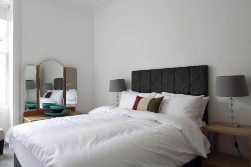 a bedroom with a large white bed with two mirrors at Stylish 2 Bedroom Bruntsfield Apartment in Edinburgh in Edinburgh