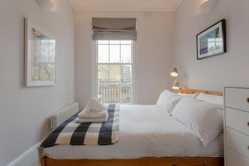 a bedroom with a large white bed with a window at Vibrant 1 Bedroom Flat In Islington With Garden in London