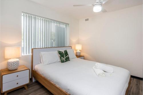 a bedroom with a white bed and a window at Stylish Apartment in Leafy South Perth in Perth