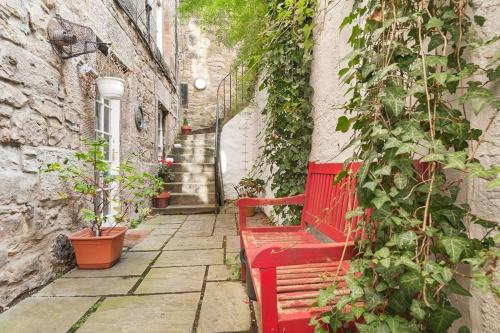 a red bench sitting in an alley with plants at Stylish Georgian Flat in New Town in Edinburgh