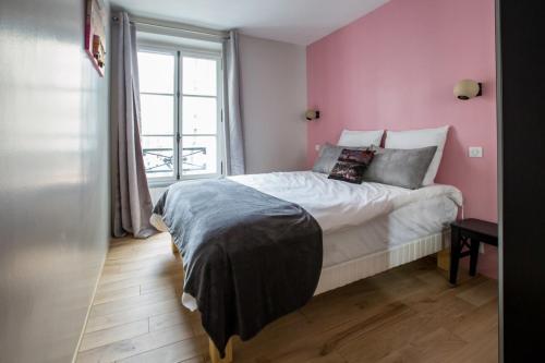 パリにあるSpacious and Charming 2 Bedroom flat à Madeleineのピンクの壁のベッドルーム1室(窓付)