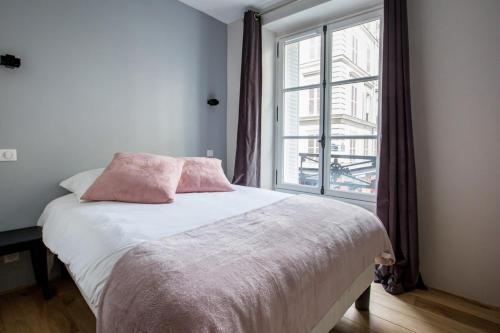 パリにあるSpacious and Charming 2 Bedroom flat à Madeleineのベッドルーム1室(ピンクの枕が付くベッド1台、窓付)