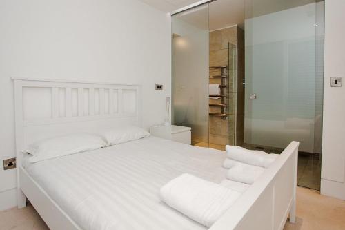 a white bedroom with a large white bed with two white towels at Beautiful Newly Renovated 2 Bed Apartment in Bank in London
