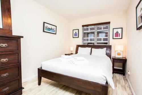 a bedroom with a large bed and a dresser at Modern and Spacious Central 1 Bedroom Apartment with Balcony in London