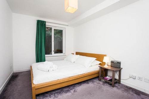 een slaapkamer met een bed en een raam bij Charming Peaceful 2 Bedroom with Parking and Garden in Londen