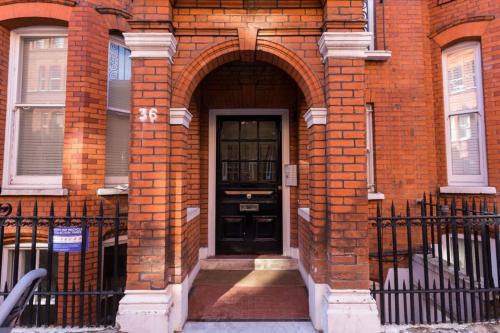 a black door in a brick building with an archway at Modern 1 bed Flat in Knightsbridge in London