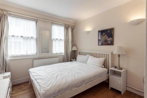 1 dormitorio con cama blanca y ventana en Bright 2 Bedroom Flat in Central London en Londres