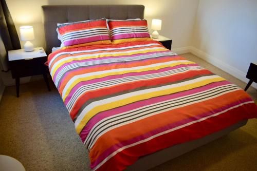 a bed with a colorful striped blanket in a room at Cosy 3 Bedroom Apartment In Trendy Haberfield in Sydney