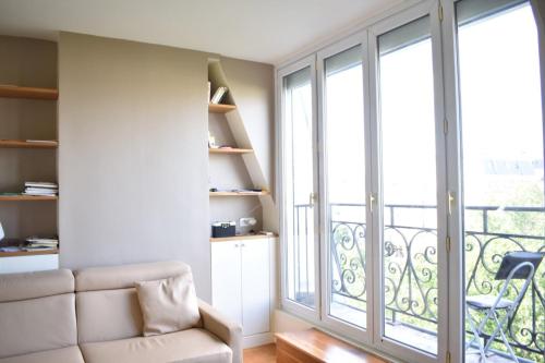 un salon avec un canapé et une grande fenêtre dans l'établissement Fully Renovated Bright Studio With High View, à Paris